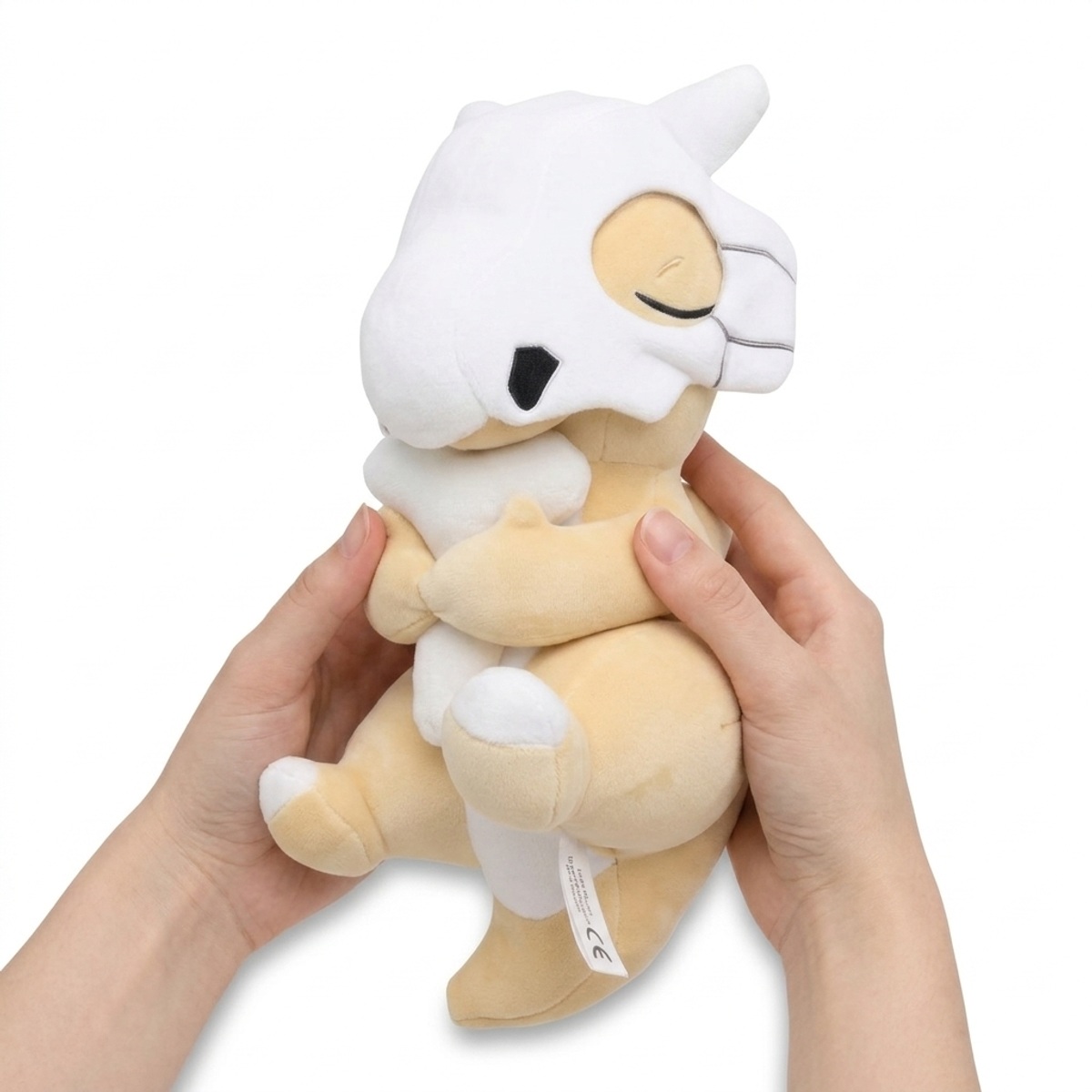 Peluche Cubone che dorme tenuta nelle mani