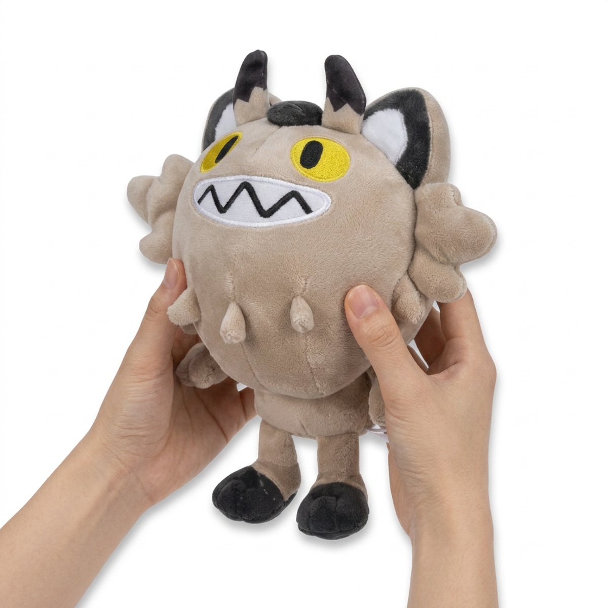 Peluche Meowth di Galar tenuto in mano